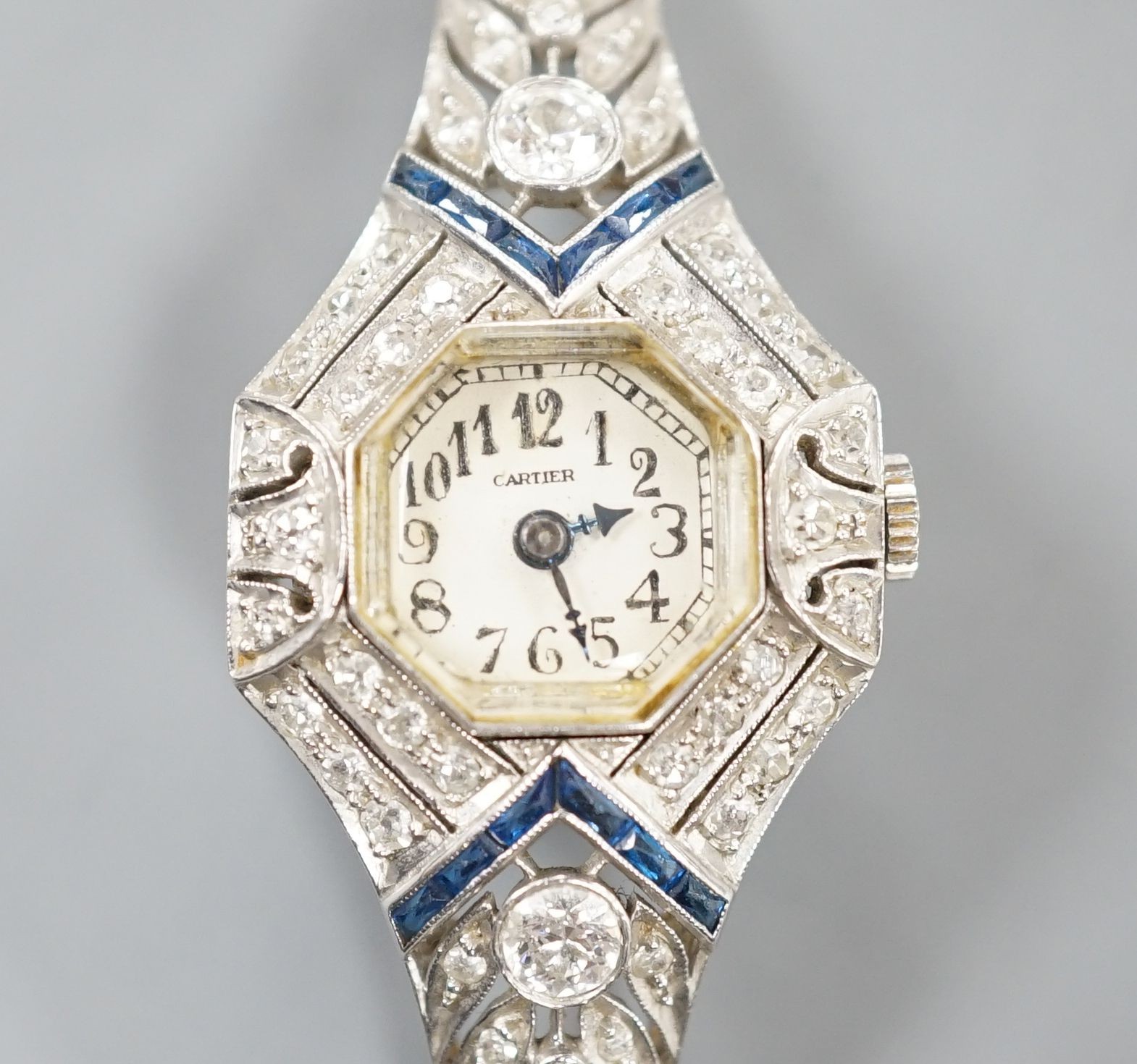 A mid 20th century white metal, synthetic sapphire? and diamond set cocktail watch, with Bucherer manual wind movement and dial bearing the signature Cartier, on a 14k white metal bracelet, case diameter 22mm, gross weig